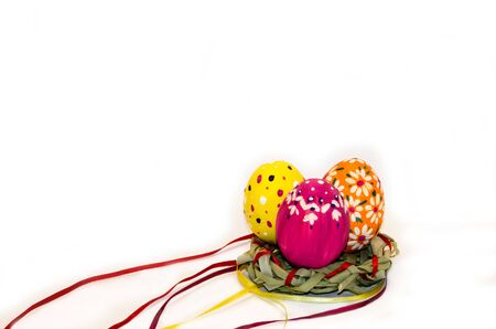Easter eggs painted in a nest of grass and ribbons on white backgroundの写真素材