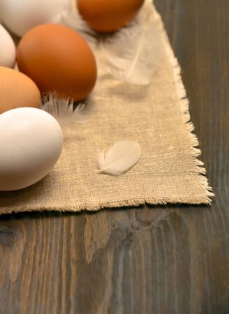 Eggs on wooden background and feathers and a napkin selective focusの写真素材