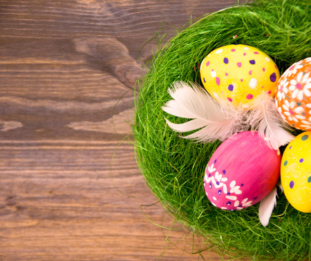 Easter eggs in a nest made of grass on wooden background selective focus