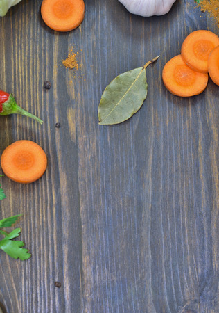 wooden brown background around the edges of the rings carrots, spices, Bay leaf, garlicの写真素材