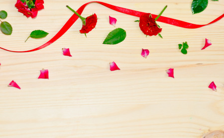 wooden background rose petals and buds and red ribbonの写真素材