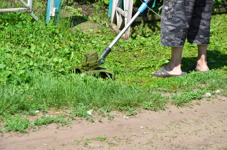 A man cuts the grass with a manual mower near the houseの写真素材