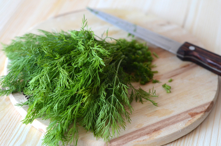 a bunch of dill cut on a wooden Board with a knife on a wooden background selective focusの写真素材