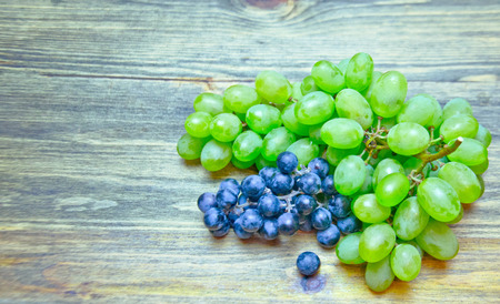 a bunch of grapes green and blue color on wooden background selective focusの写真素材
