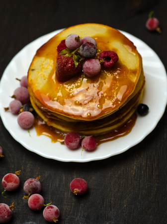pancakes with jam and berries on wooden black background selective focus