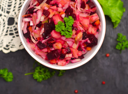 Russian salad vinaigrette next to greens, proper nutrition, vegetarian, selective focus on wooden backgroundの写真素材