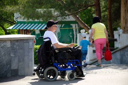 disabled person with a chair with manual control on the street in the summerのeditorial素材
