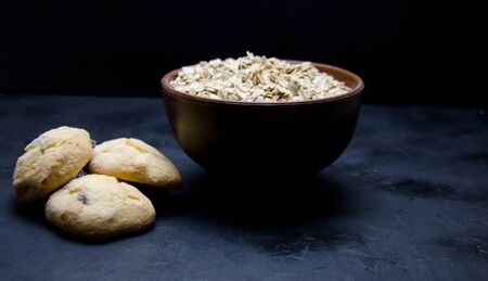oatmeal cookies and a Cup of dry oatmeal on a black background blurredの写真素材