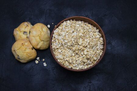 oatmeal cookies and a Cup of dry oatmeal on a black background blurred imageの写真素材