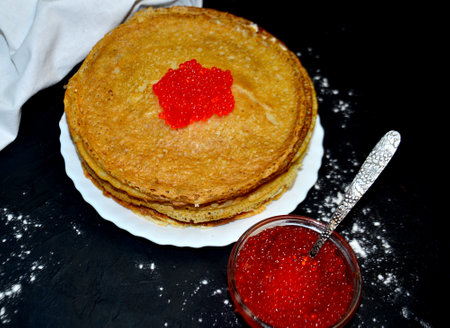 pancakes in a plate with red caviar on a black backgroundの写真素材
