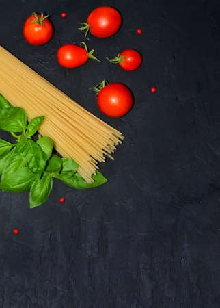 basil spaghetti and tomatoes on a black background selective focus with a place to recordの写真素材