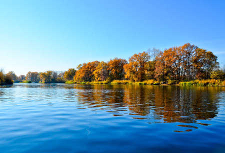 beautiful autumn landscape on the river orange trees reflected in the river selective focus