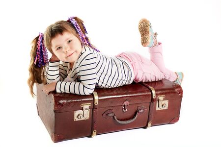 beautiful smiling toddler girl laying on retro suitcase, white backgroundの写真素材