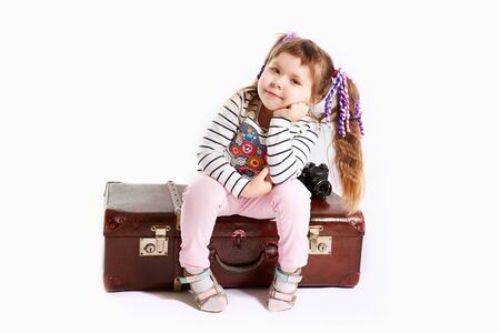 beautiful toddler girl sitting on retro suitcase, white backgroundの写真素材