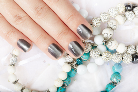Hand with gray metallic manicured nails and colorful braceletsの写真素材