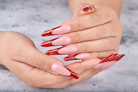 Hands with long red artificial french manicured nailsの写真素材
