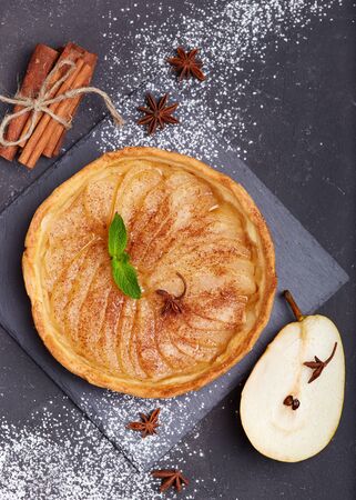 Delicious tart with pears, cinnamon and sugar powder. Open pie, sweet taste. Autumn dessert.の写真素材