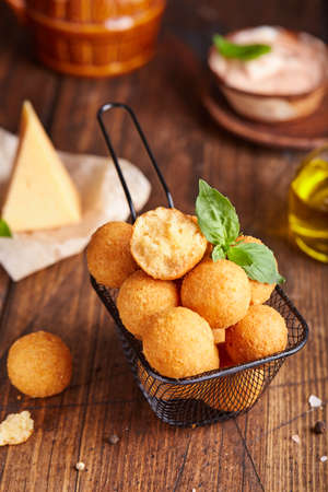 Deep fried Cheese balls. Delicious homemade appetizer. Freshly baked croquettes, served with basil leafs and sauce.の写真素材
