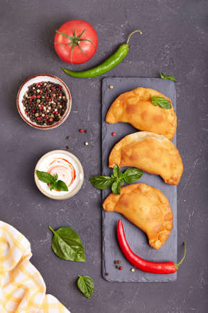 Empanada pies with minced beef meat. Freshly baked small pies served with basil leafs and sauce.