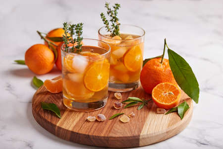 Ice tea with orange juice, ice cubes, and thymes. Refreshing cold spring and summer citrus beverage.