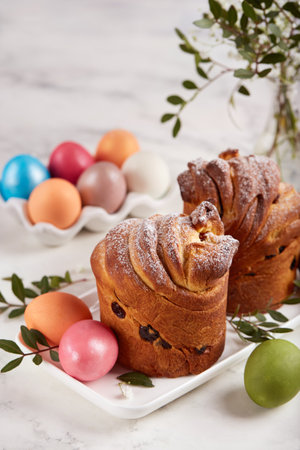 Traditional Easter Cruffin buns made from yeast dough with raisins covered with sugar powder. Colored Easter eggs.の写真素材
