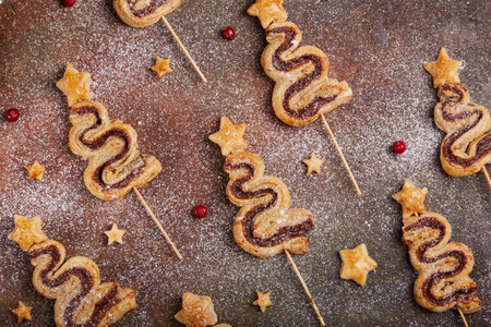 Christmas tree shape puff pastry cakes with chocolate filling and sugar powder. Delicious homemade New Year sweet baking.の写真素材
