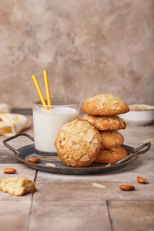 Delicious homemade butter cookies with almond petals, served with glass of milk. Blank space for...