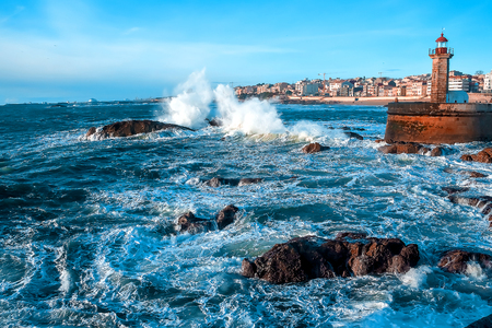 The waves of the Atlantic Ocean crash against the rocks at sunset by the lighthouseのeditorial素材