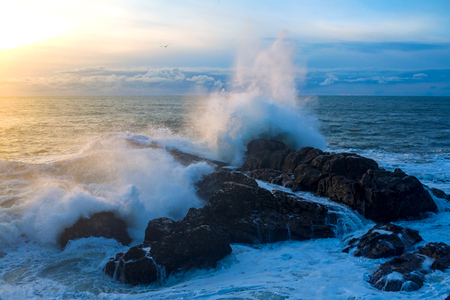 Waves of the Atlantic Ocean crashing against a rock at sunset.の写真素材