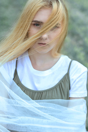 close-up portrait of a cute beautiful young blonde girl with frecklesの写真素材
