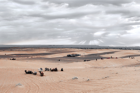 Sunrise in the western part of the Sahara Desert in Morocco. The sun's rays break through the clouds and sanctify the campsite and camels at the foot of the desert.の写真素材