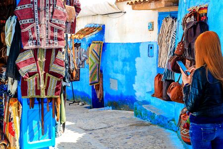 CHEFCHAOUEN, MOROCCO - APRIL 24, 2019: Colorful Moroccan fabrics and handmade souvenirs on the street in the blue city Chefchaouen, Morocco, Africa.の写真素材
