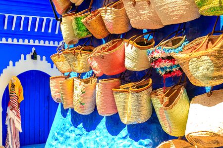 CHEFCHAOUEN, MOROCCO - APRIL 24, 2019: Colorful Moroccan fabrics and handmade souvenirs on the street in the blue city Chefchaouen, Morocco, Africa.の写真素材
