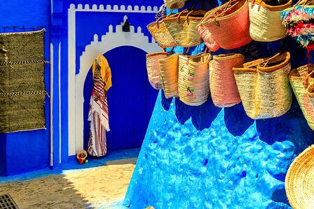 CHEFCHAOUEN, MOROCCO - APRIL 24, 2019: Colorful Moroccan fabrics and handmade souvenirs on the street in the blue city Chefchaouen, Morocco, Africa.の写真素材
