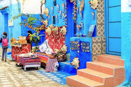 CHEFCHAOUEN, MOROCCO - APRIL 24, 2019: Colorful Moroccan fabrics and handmade souvenirs on the street in the blue city Chefchaouen, Morocco, Africa.の写真素材