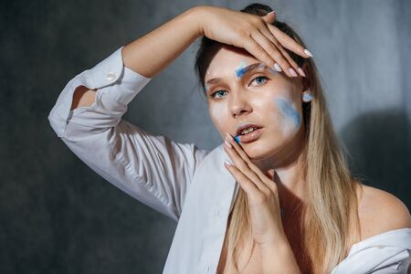 Creative fashion beauty portrait of beautiful young blonde woman with hairstyle. Model girl with professional make-up and body art on gray background.の写真素材