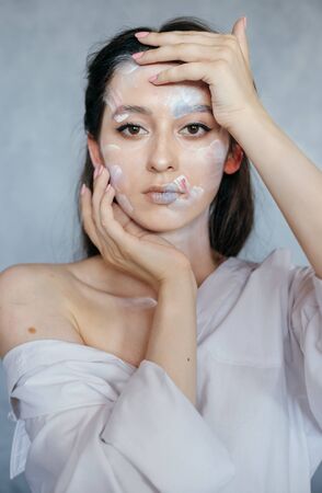 Creative fashion beauty portrait of beautiful young woman with hairstyle. Model girl with professional make-up and body art on gray background.の写真素材