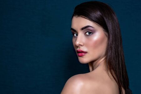 Brunette girl with long and shiny long hair and with perfect make-up on a blue background. Belarus