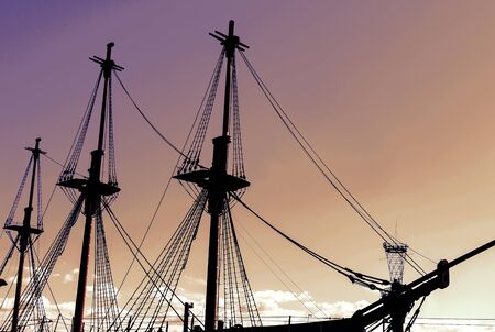 Silhouette of an old, ancient, wooden ship with masts on a sunset background.の写真素材