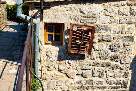 Authentic house with a stone wall, with beautiful old open windows and with green shutters, and with vases on the window. Montenegroの写真素材