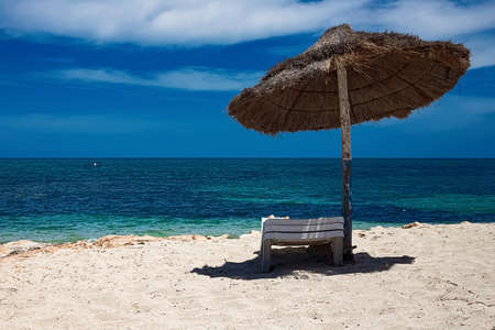 . A view of the Mediterranean coast with birch water on which a sun lounger and an umbrella are...