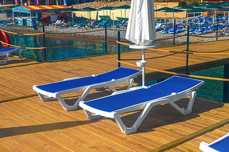 View of the pier with blue sun loungers and white umbrellas on the seashore in Kemer. Turkeyの写真素材