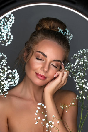 Portrait of a smiling beautiful, sweet girl on a gray background with white flowers.の写真素材