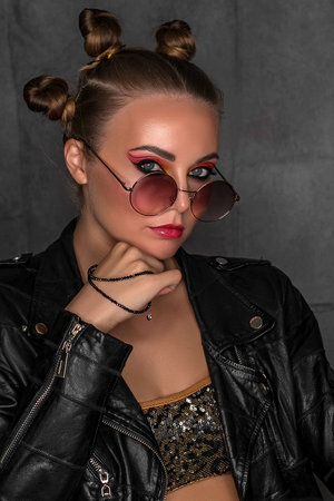 Portrait of a young sassy girl with blond hair in the studio on a gray background.