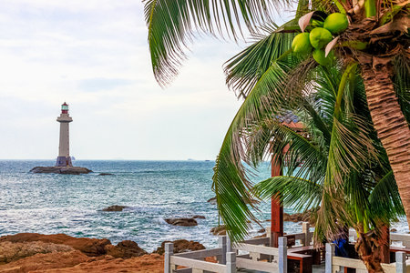 View of a lighthouse in the sea near a rocky shore with palm trees. End of the World Park, Sanya.の写真素材