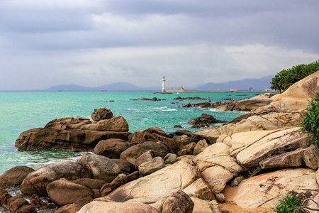 View of the lighthouse in the sea near the rocky shore. Heavenly Grottoes Park, Sanya, China