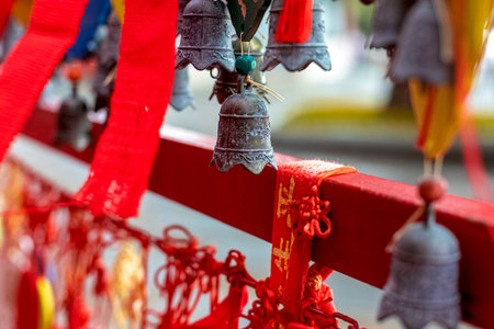 Carved bronze bells and red ribbons with Chinese characters at a temple.