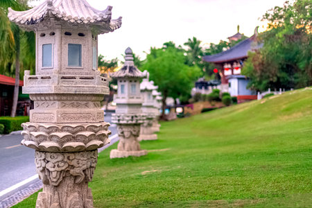 Stone lanterns line a path in Nanshan Park, surrounded by greenery. Chinese architecture is visible in the background.の写真素材
