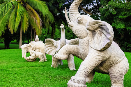 Stone sculptures of elephants in Nanshan Park, Sanya, Hainan, against a backdrop of green palm treesの写真素材