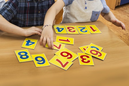 Kids are playing. Educational games. A child in kindergarten. The hands of a child. Maths. Cards for...